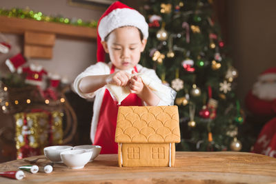 Close-up of gingerbread house on table with girl in background