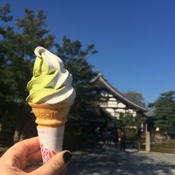 Cropped image of person holding ice cream against clear blue sky