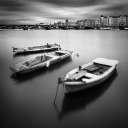 Boats moored in sea against sky in city