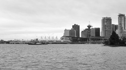 Modern buildings by river against sky in vancouver canada