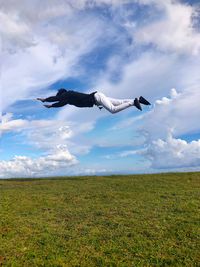 Young man levitating over land against sky