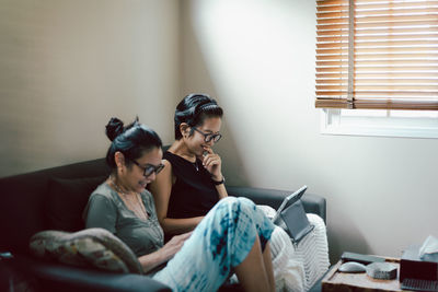 Side view of two woman using digital tablet at home