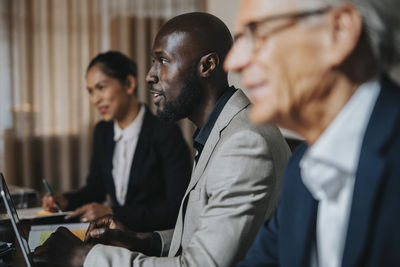 Bald businessman discussing ideas with male and female colleague during meeting