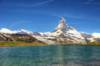 Scenic view of snowcapped mountains against blue sky