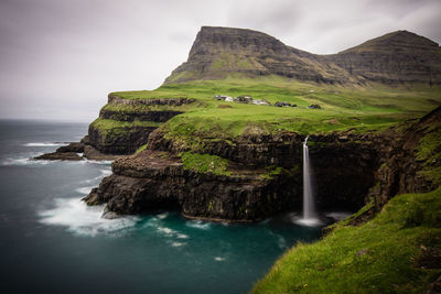 Scenic view of sea and waterfall against sky 