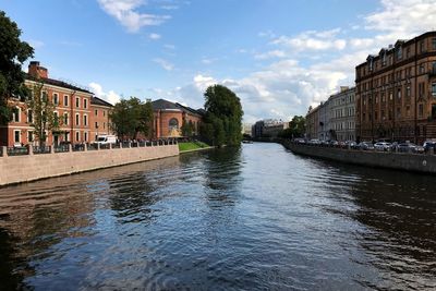 Canal amidst buildings in city against sky