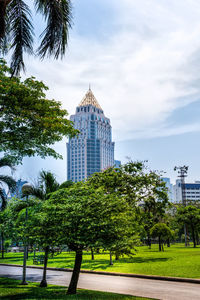 Trees and buildings against cloudy sky