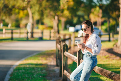 Side view of young woman sitting on railing