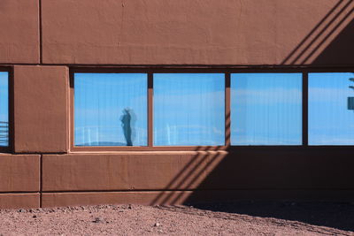 Man standing by window against sky