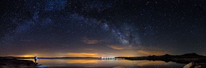 Panoramic view of lake against star field at night