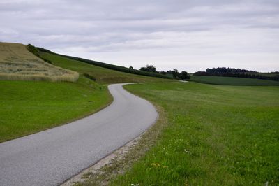 Road amidst field against sky