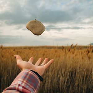 Cropped image of person standing on field against cloudy sky