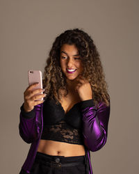 Young woman using smart phone against gray background