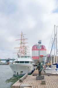 Sailboats moored at harbor against sky