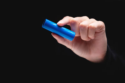 Close-up of hand holding electronic cigarette against black background