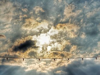 Low angle view of birds perching on cable against sky