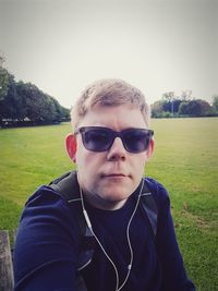 Portrait of sunglasses on field against clear sky