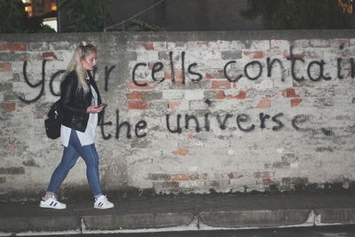 Full length of man standing against graffiti wall