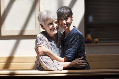 Nurse embracing senior woman in retirement home