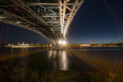 Illuminated bridge over river at night