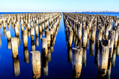 Panoramic view of wooden posts in sea against sky