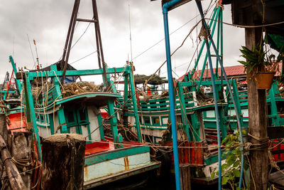 Fishing boats moored in water against sky