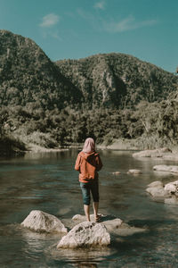 Full length of woman standing on rock at shore