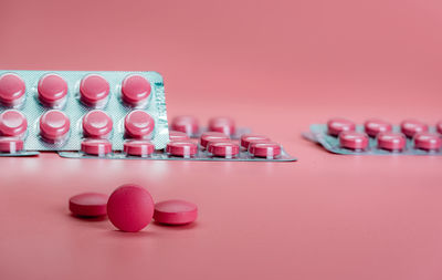 Pink tablet pills and blister pack of pills on pink background. prescription drug. vitamins, mineral