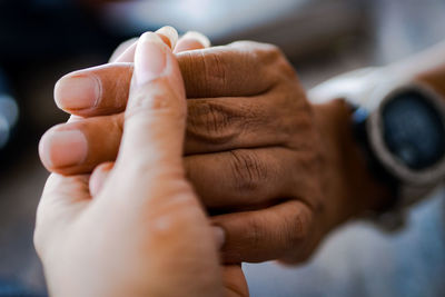 Close-up of couple holding hand indoors