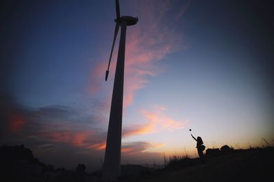 Silhouette man with arms outstretched against sky at sunset