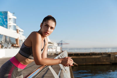 Woman looking away while leaning on railing against sky