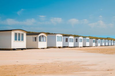 Beach huts by buildings against sky