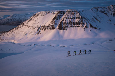 Group of people backcountry skiing at sunrise in iceland