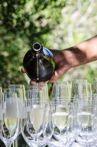 Closeup of a hand pouring the last droplet of sparking wine into wine glasses at outdoor part. 