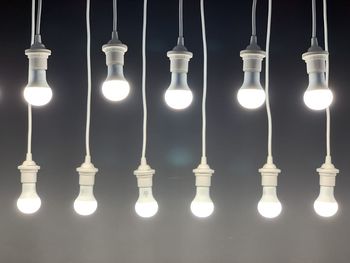 Close-up of illuminated light bulb hanging against black background