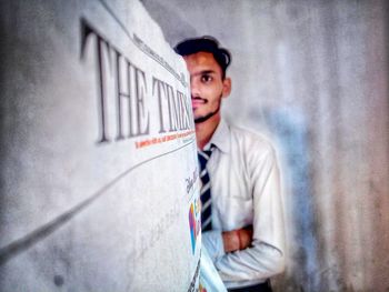 Portrait of young man standing against wall