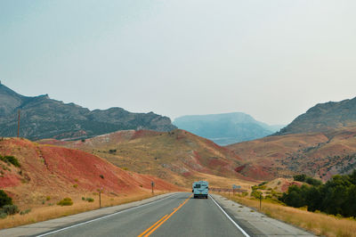 Road leading towards mountains against clear sky