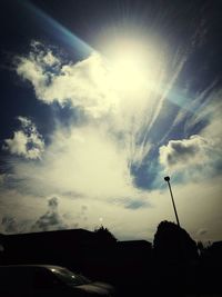 Low angle view of sun shining through clouds