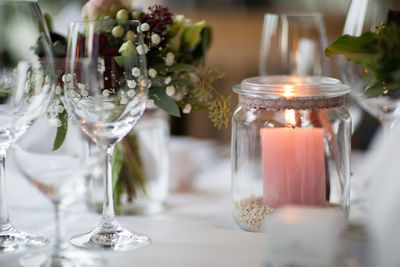 Close-up of illuminated candle in glass jar on dining table