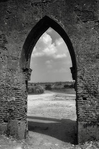 Arch on wall of old building against sky