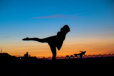 Silhouette women performing ballet dance at beach against sky during sunset