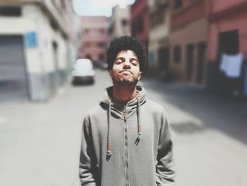 Portrait of young man standing on street in city
