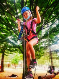 Portrait of a smiling girl on tree in  adventure park . 