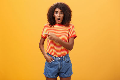 Portrait of young man standing against orange background