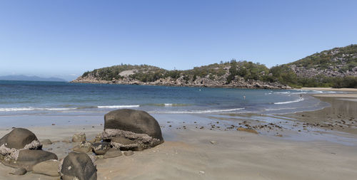 Rocks on beach against clear sky