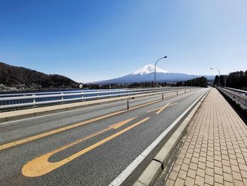 Road leading towards mountain against clear sky