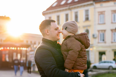 A happy father and three year old son hug in a city street. warm relationships between parents 