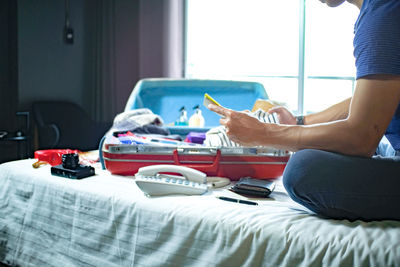 Midsection of man using mobile phone on bed