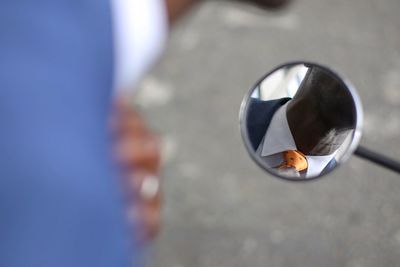 Reflection of man wearing necktie seen in side-view mirror