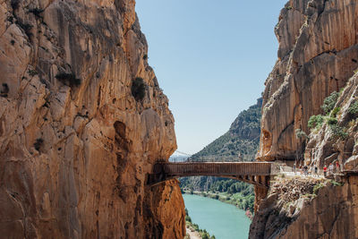 Footbridge over mountain against clear sky